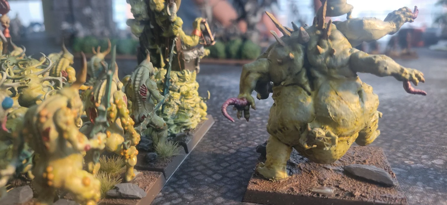 Close-up of pale green Nurgle daemons advancing across a cobbled gaming table.
